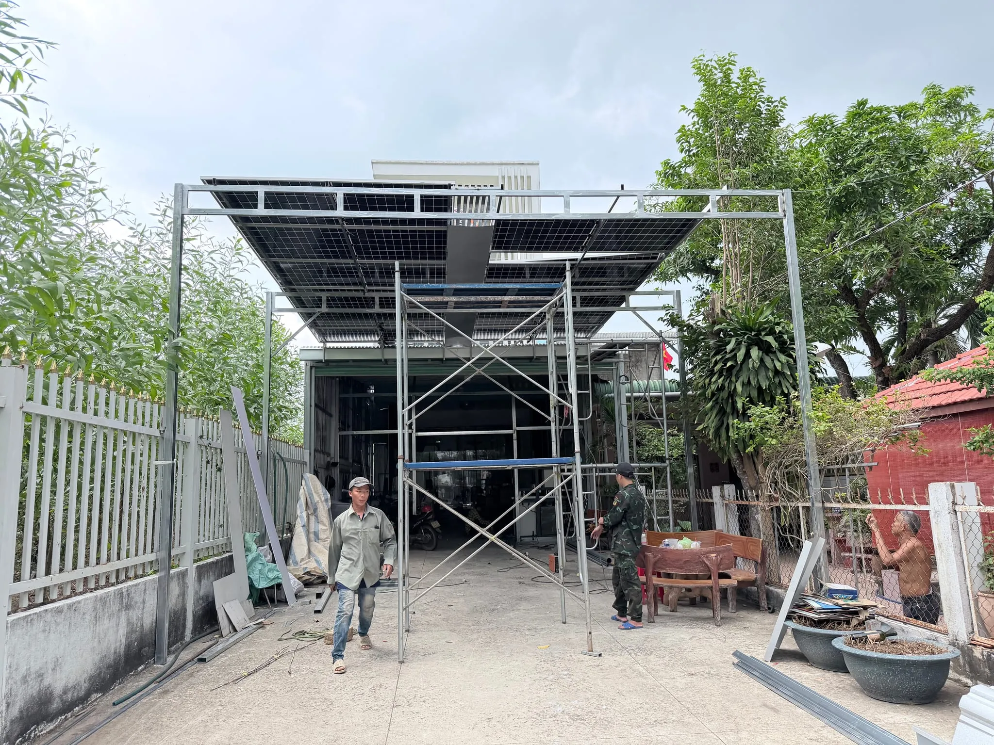 Khung thép mái che lợp bằng tấm pin trước sân nhà, giàn giáo còn dựng trong lúc thi công